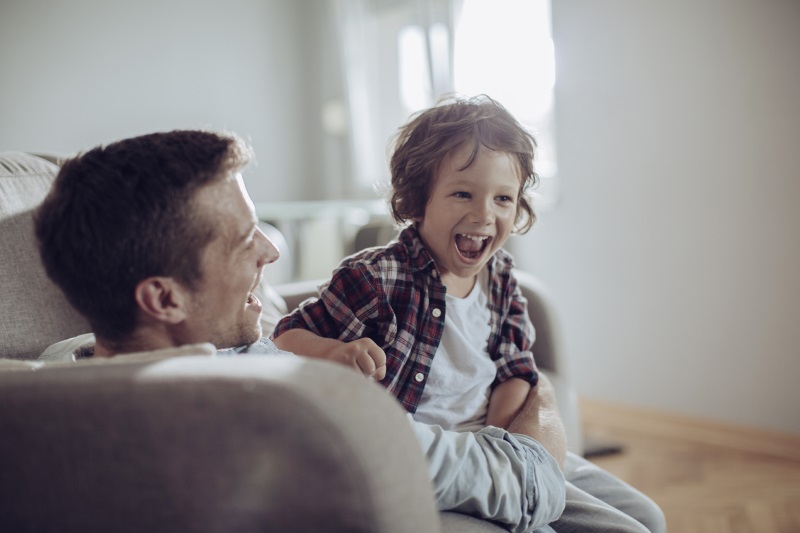 photo of smiling father and son sitting on a couch